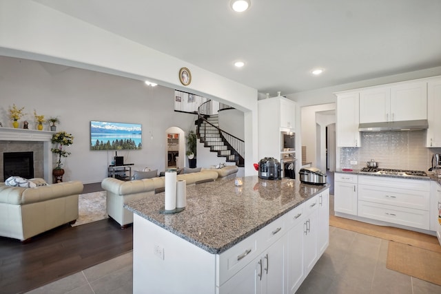 kitchen featuring a fireplace, light hardwood / wood-style flooring, backsplash, and dark stone counters