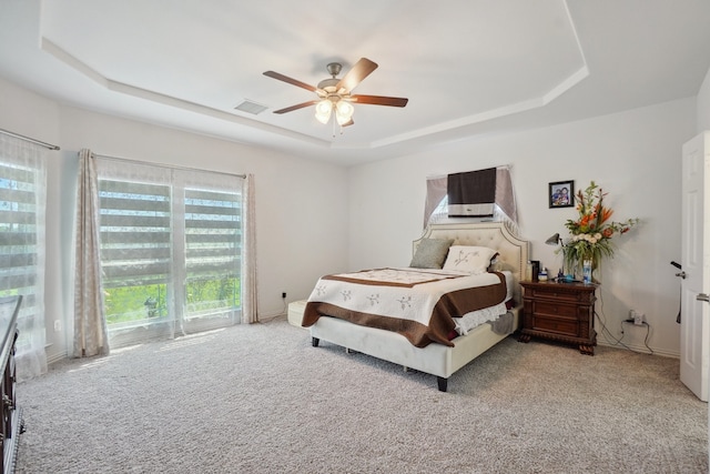 carpeted bedroom with ceiling fan and a raised ceiling