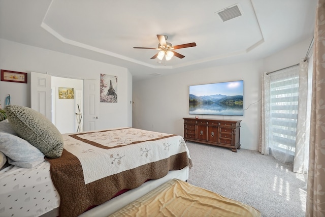 carpeted bedroom with ceiling fan and a tray ceiling