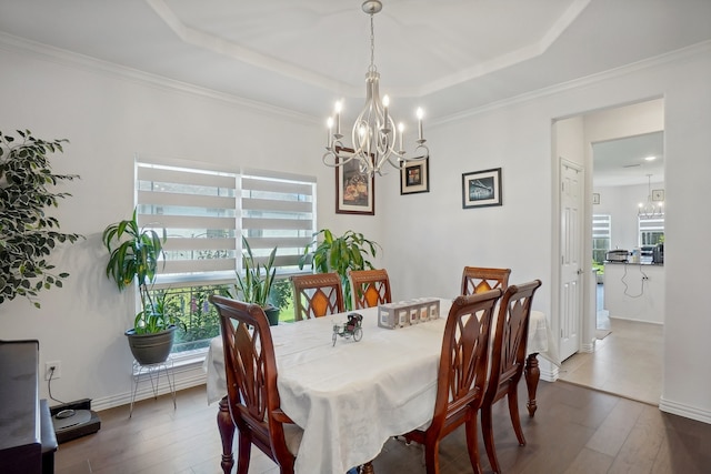 dining space with a tray ceiling, crown molding, an inviting chandelier, and wood-type flooring