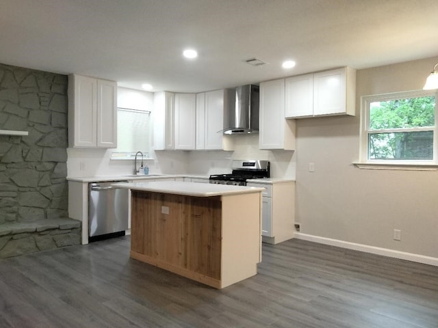 kitchen with appliances with stainless steel finishes, a center island, dark wood-type flooring, and wall chimney exhaust hood