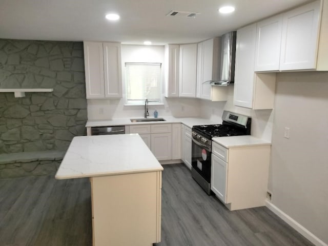 kitchen featuring white cabinetry, hardwood / wood-style floors, sink, wall chimney range hood, and stainless steel range with gas cooktop