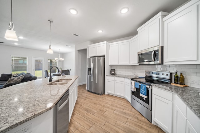 kitchen with white cabinets, light wood-type flooring, sink, pendant lighting, and stainless steel appliances