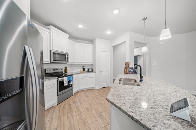 kitchen with appliances with stainless steel finishes, light hardwood / wood-style flooring, white cabinetry, and hanging light fixtures