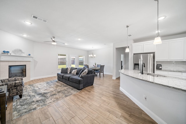 living area featuring light wood-style flooring, baseboards, visible vents, and a tile fireplace