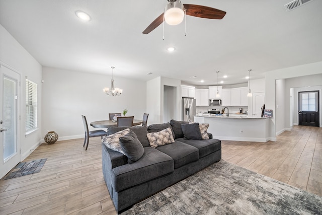 living room with sink, light hardwood / wood-style flooring, a tiled fireplace, and ceiling fan