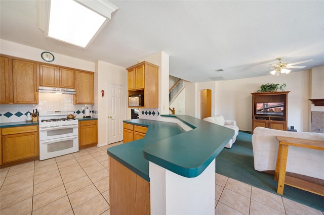 kitchen with light tile patterned floors, ceiling fan, tasteful backsplash, and range with two ovens