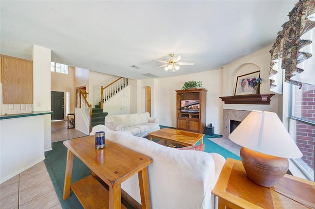 living room with a tile fireplace, light tile patterned flooring, and ceiling fan