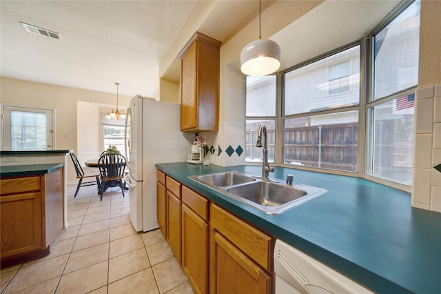 kitchen featuring a notable chandelier, white appliances, light tile patterned flooring, pendant lighting, and sink