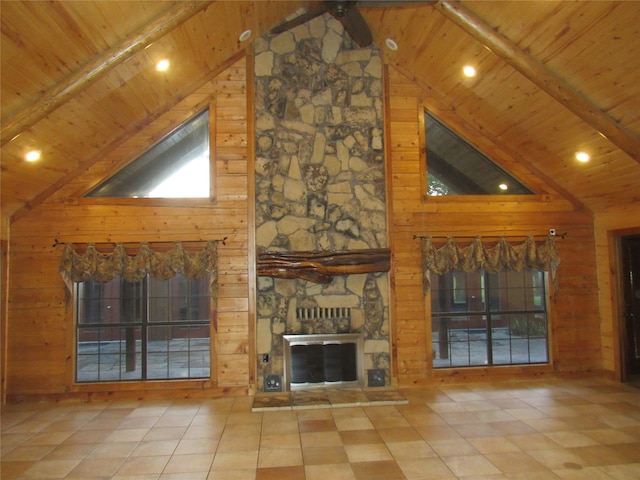 unfurnished living room with wooden ceiling, wood walls, and a stone fireplace