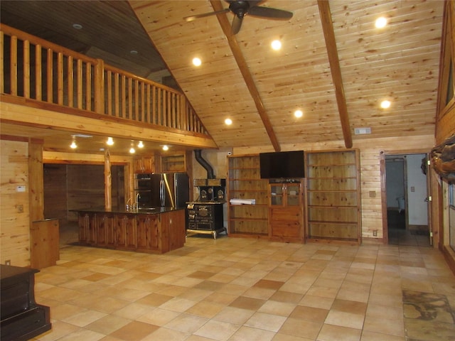 interior space with brown cabinets, freestanding refrigerator, wood ceiling, a wood stove, and wood walls