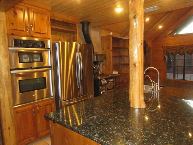 kitchen with appliances with stainless steel finishes, wood ceiling, a wood stove, lofted ceiling, and dark stone counters