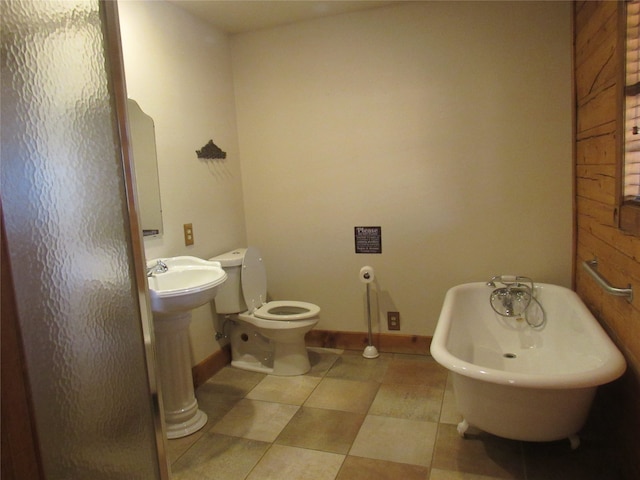 full bathroom featuring toilet, a sink, baseboards, and a freestanding bath