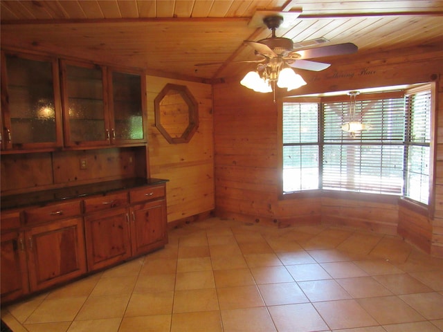 interior space featuring light tile patterned floors, dark countertops, wooden ceiling, glass insert cabinets, and wood walls