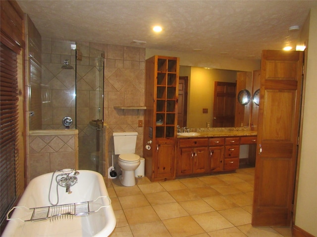 bathroom with tile patterned flooring, a soaking tub, a textured ceiling, and vanity