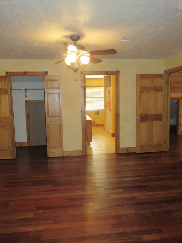 unfurnished bedroom featuring a textured ceiling, connected bathroom, ceiling fan, and dark hardwood / wood-style floors