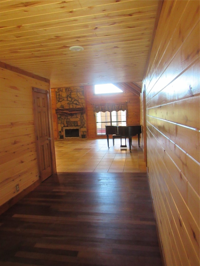 interior space featuring lofted ceiling, wooden ceiling, wooden walls, a fireplace, and dark wood finished floors