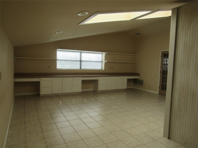 spare room with lofted ceiling, light tile patterned floors, visible vents, and built in study area