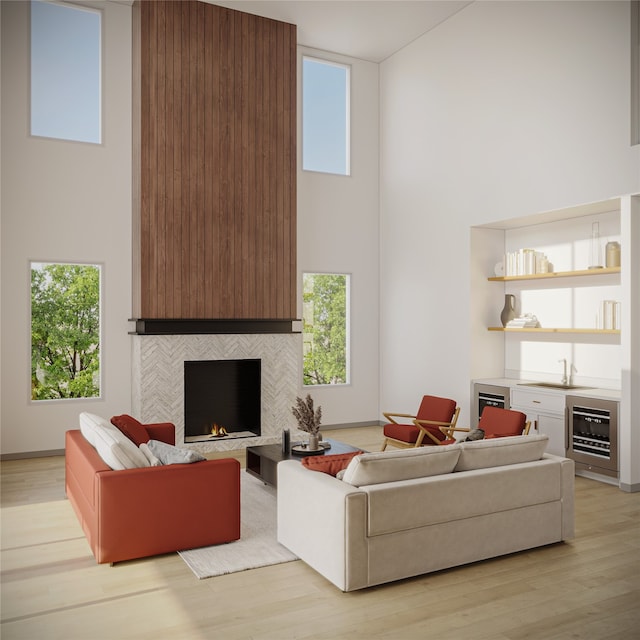 living room with a high ceiling, light hardwood / wood-style flooring, a tile fireplace, and beverage cooler