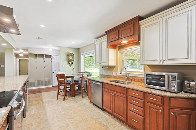 kitchen with light stone countertops, sink, stainless steel appliances, and exhaust hood