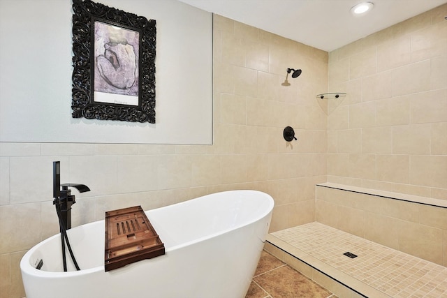 bathroom with tile patterned flooring, tile walls, and plus walk in shower