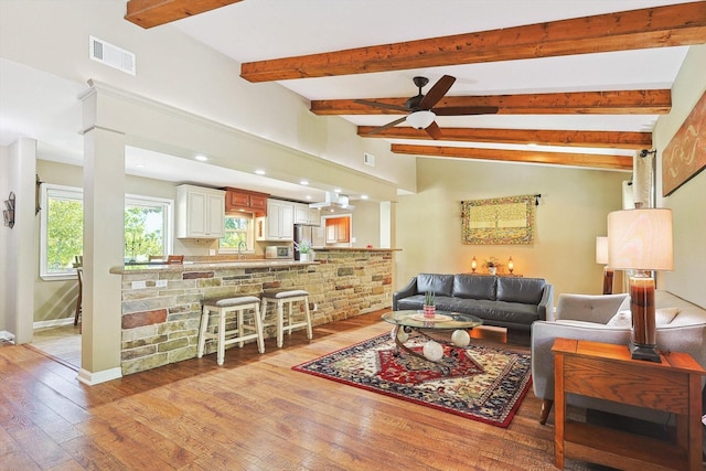 living room featuring ceiling fan, vaulted ceiling with beams, and light hardwood / wood-style flooring