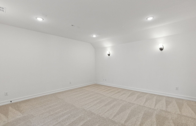 spare room featuring light colored carpet and vaulted ceiling