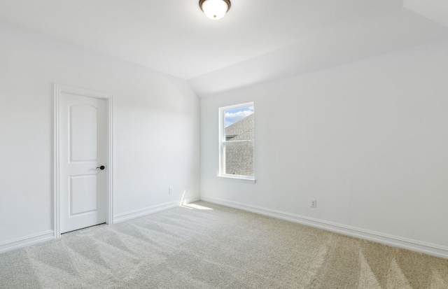 empty room featuring carpet and vaulted ceiling