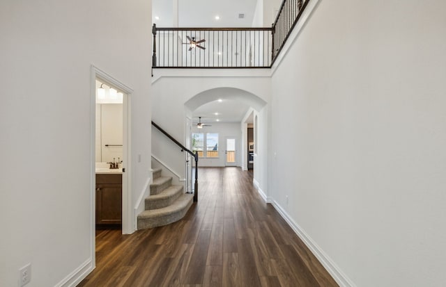 foyer with ceiling fan, sink, dark wood-type flooring, and a high ceiling