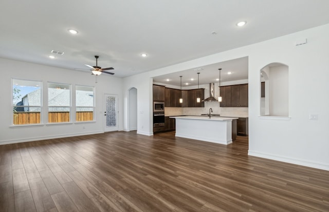 unfurnished living room featuring ceiling fan, sink, and dark hardwood / wood-style floors