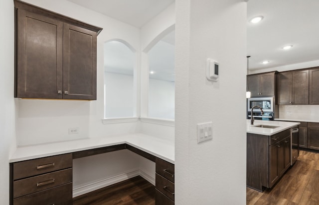 kitchen featuring backsplash, dark brown cabinets, sink, built in desk, and dark hardwood / wood-style floors