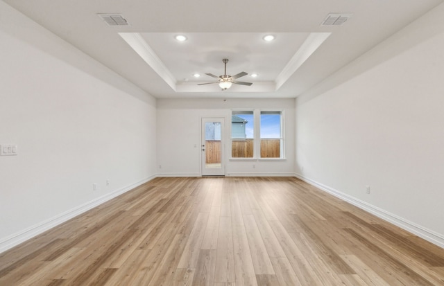 spare room with a raised ceiling, ceiling fan, crown molding, and light wood-type flooring