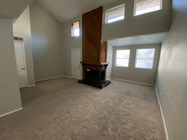 unfurnished living room featuring light colored carpet, high vaulted ceiling, and plenty of natural light