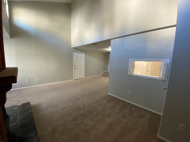 unfurnished living room with carpet floors and a high ceiling