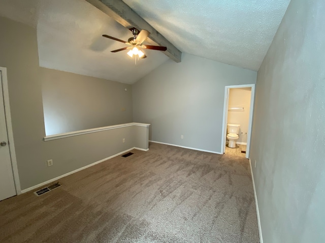 unfurnished bedroom featuring vaulted ceiling with beams, carpet, ensuite bath, a textured ceiling, and ceiling fan