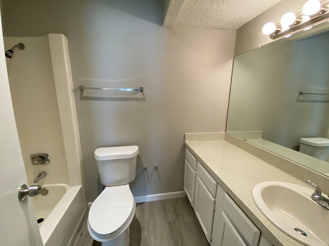 full bathroom featuring toilet, shower / bathtub combination, vanity, hardwood / wood-style flooring, and a textured ceiling