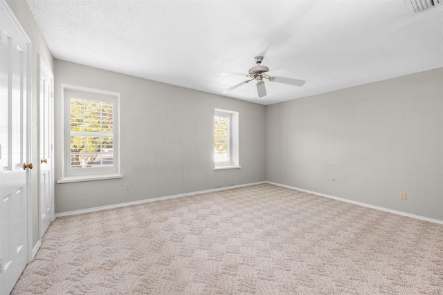 carpeted empty room featuring ceiling fan and a textured ceiling