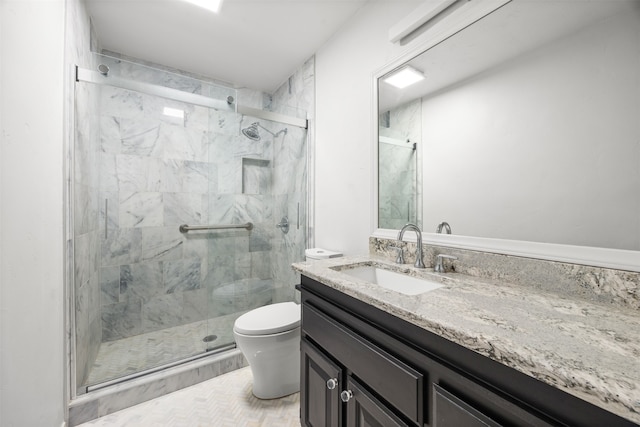 bathroom featuring a shower with door, vanity, and toilet