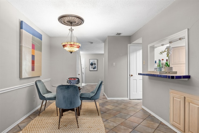 tiled dining room with bar and a textured ceiling