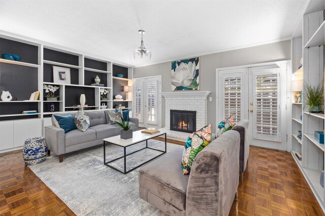 living room featuring dark parquet floors, a fireplace, crown molding, a textured ceiling, and french doors