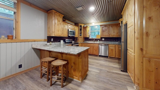 kitchen with appliances with stainless steel finishes, light hardwood / wood-style flooring, kitchen peninsula, tasteful backsplash, and wood ceiling