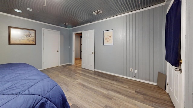 bedroom with ornamental molding and wood-type flooring