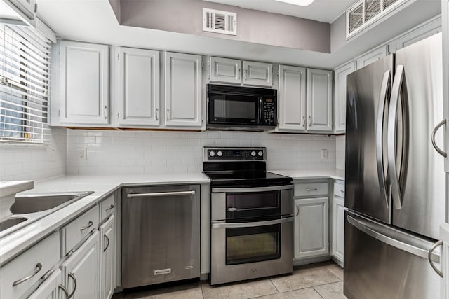 kitchen with light tile patterned floors, stainless steel appliances, tasteful backsplash, and gray cabinetry