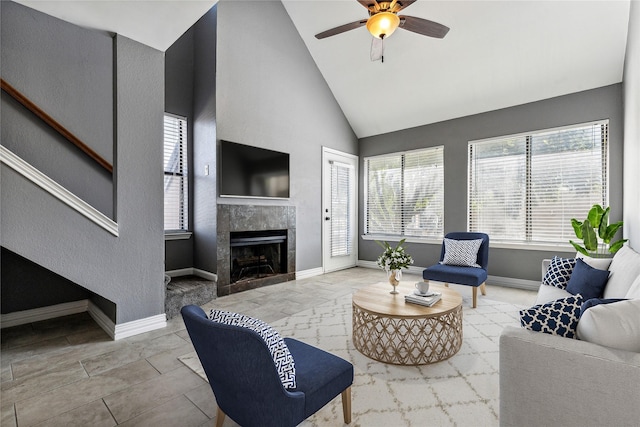 living room with high vaulted ceiling, a tile fireplace, a ceiling fan, and baseboards