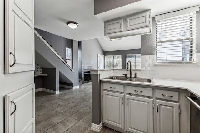 kitchen featuring sink, dark tile patterned floors, stainless steel dishwasher, and vaulted ceiling