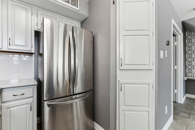 kitchen featuring white cabinets, tasteful backsplash, stainless steel fridge, and light tile patterned flooring