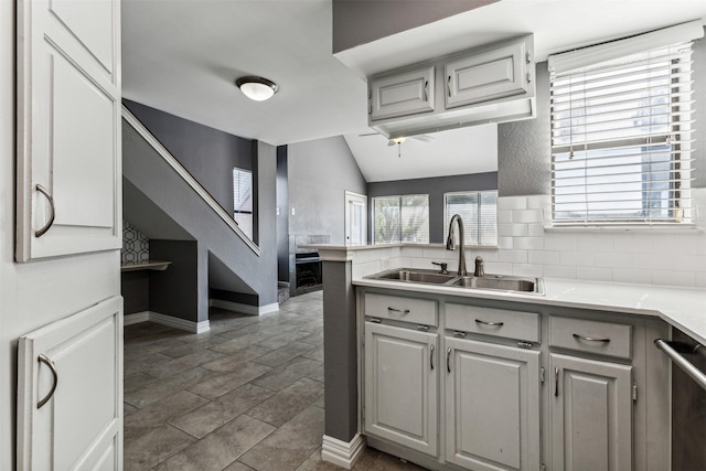 kitchen featuring lofted ceiling, a wealth of natural light, a sink, and dishwasher