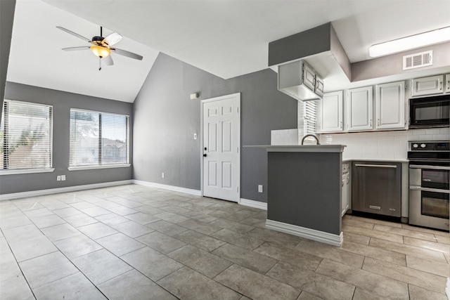 kitchen with decorative backsplash, black microwave, vaulted ceiling, range, and light tile patterned flooring