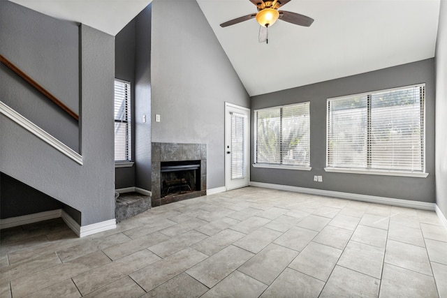 unfurnished living room featuring ceiling fan, light tile patterned flooring, a tile fireplace, and a healthy amount of sunlight