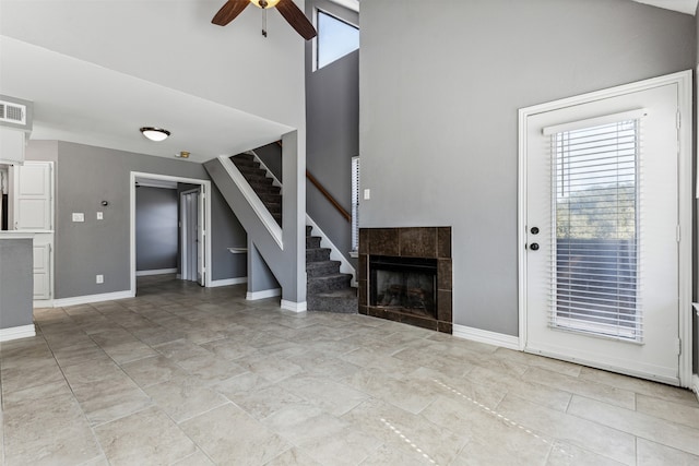 unfurnished living room with ceiling fan, a tile fireplace, and light tile patterned floors